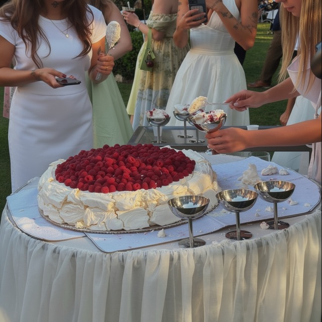 Guests gathering around the wedding cake topped with fresh raspberries